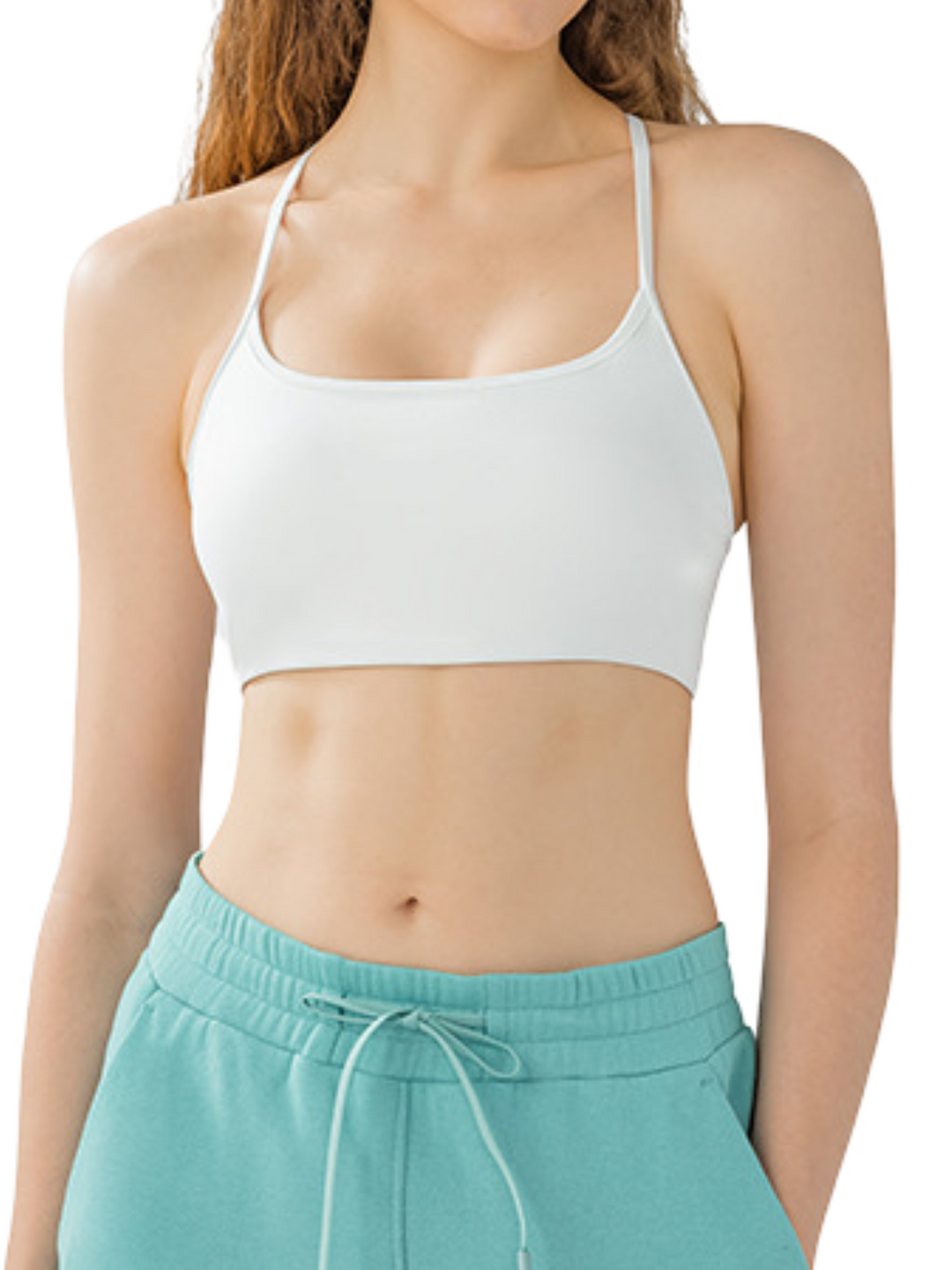 Woman wearing the Navalora Fit Olivia white sports bra and teal pants on a white background