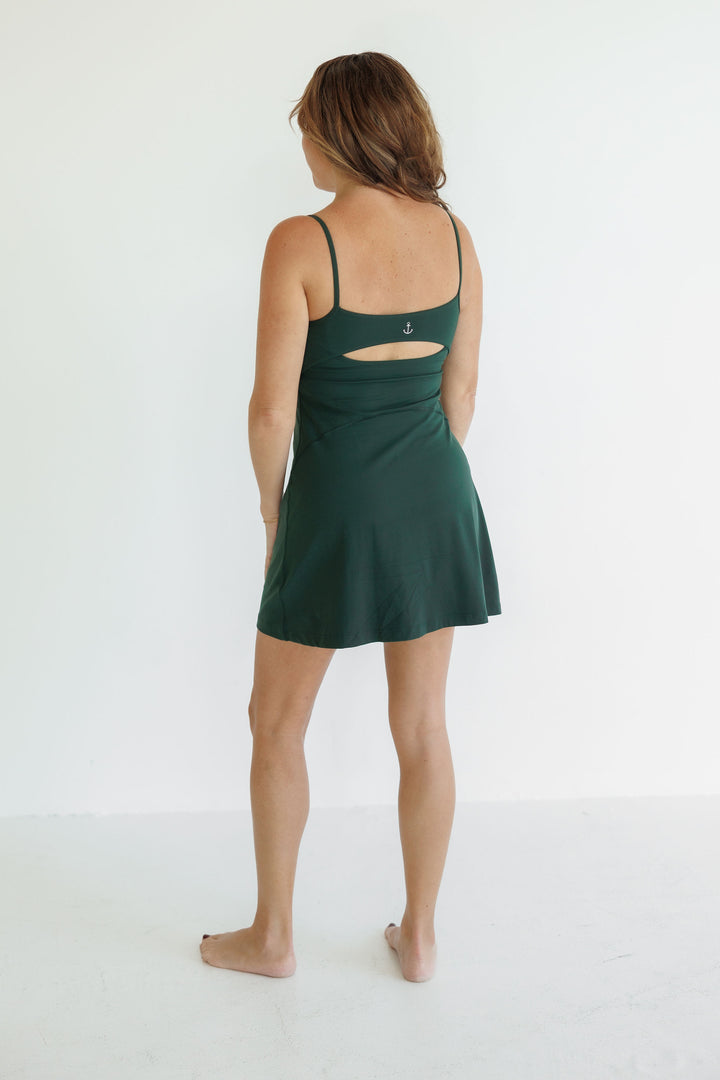 Navalora Fit Hunter Green Jordan Active Dress Worn by a Model in the Studio with a white background.  Featuring the cutout on the back of the dress and the Anchor Logo