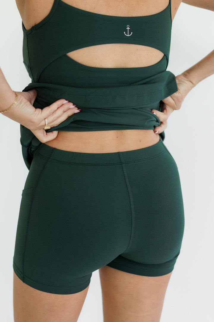 Person wearing a green sports bra and shorts set on a white background